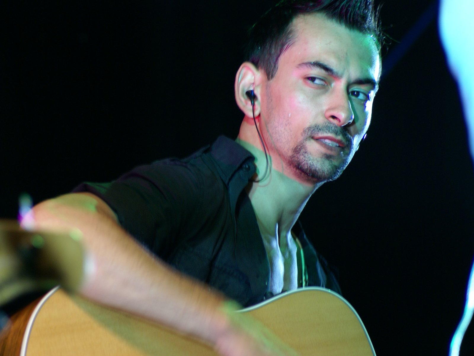 Alex Bodnar playing acoustic guitar on stage, looking toward the audience